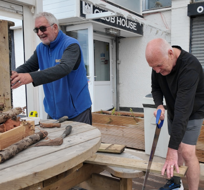 Two older men working together to build a bug hotel, a habitat for beneficial insects